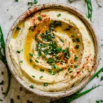 3 Vegan High Protein Snacks That Build Muscle Fast and Clean 29 Creamy hummus in a bowl topped with olive oil, chives, and paprika