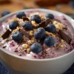 Protein Fluff topped with blueberries, granola, and dark chocolate shavings