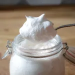 Protein Marshmallow Fluff Recipe – Fluffy, Sweet & Guilt-Free 5 Protein marshmallow fluff on spoon above glass jar, fluffy and creamy