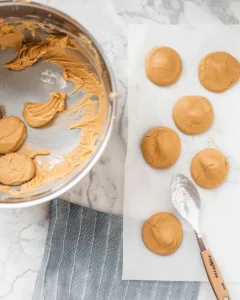 4-Ingredient Chocolate Peanut Butter No Bake Cookies (High-Protein & Ready in 5 Minutes) 14 Peanut butter dough shaped into cookies on parchment paper next to mixing bowl