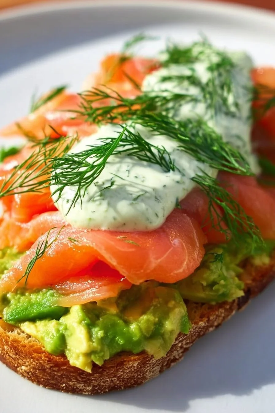 Avocado toast topped with smoked salmon and garnished with herbs.