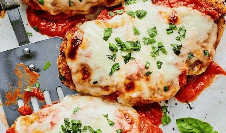 Delicious plate of Ina Garten's Chicken Parmesan garnished with fresh basil.