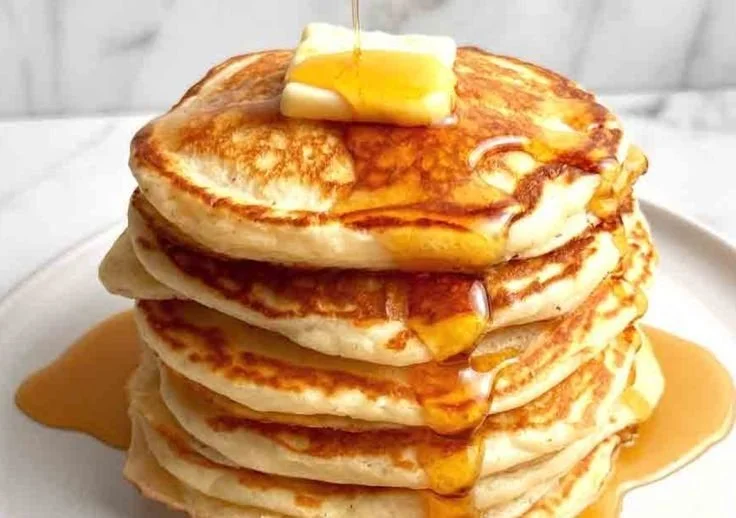 Delicious stack of Greek yogurt pancakes topped with fresh berries and syrup
